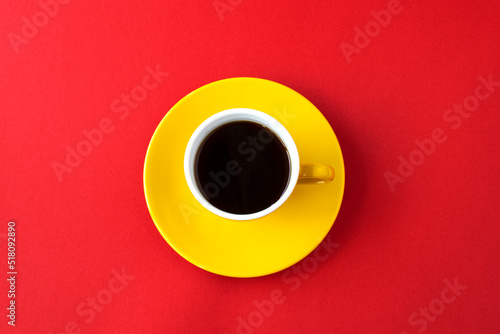 赤いの紙の上の黄色のコーヒーカップのコーヒー