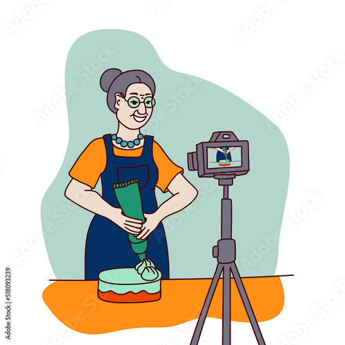 An elderly woman confectioner prepares a cake. A female blogger or vlogger who creates video content for a cooking and baking channel.