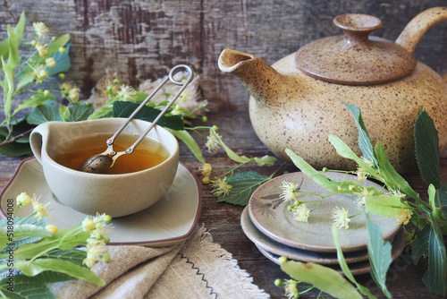 Cup of herbal limeleaf tea with linden flowers on old wooden background photo