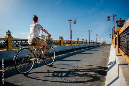 Mujer cruzando un puente en su bicicleta al atardecer de un día soleado photo