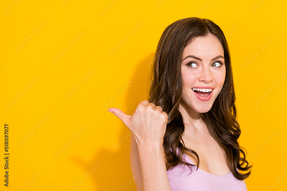 Portrait of positive lady look indicate thumb empty space promotion isolated on yellow color background Portrait of positive lady look indicate thumb empty space promotion isolated on yellow color background