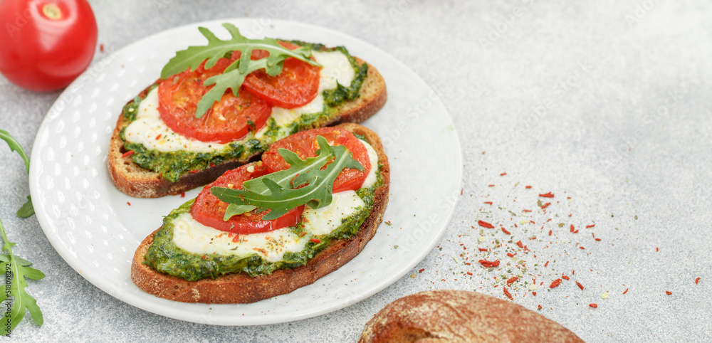 Delicious black rye bread sandwiches.with pesto, buratta cheese or mozzarella, tomatoes and fresh arugula. Brunch. Mediterranean cuisine. Selective focus Delicious black rye bread sandwiches.with pesto, buratta cheese or mozzarella, tomatoes and fresh arugula. Brunch. Mediterranean cuisine. Selective focus