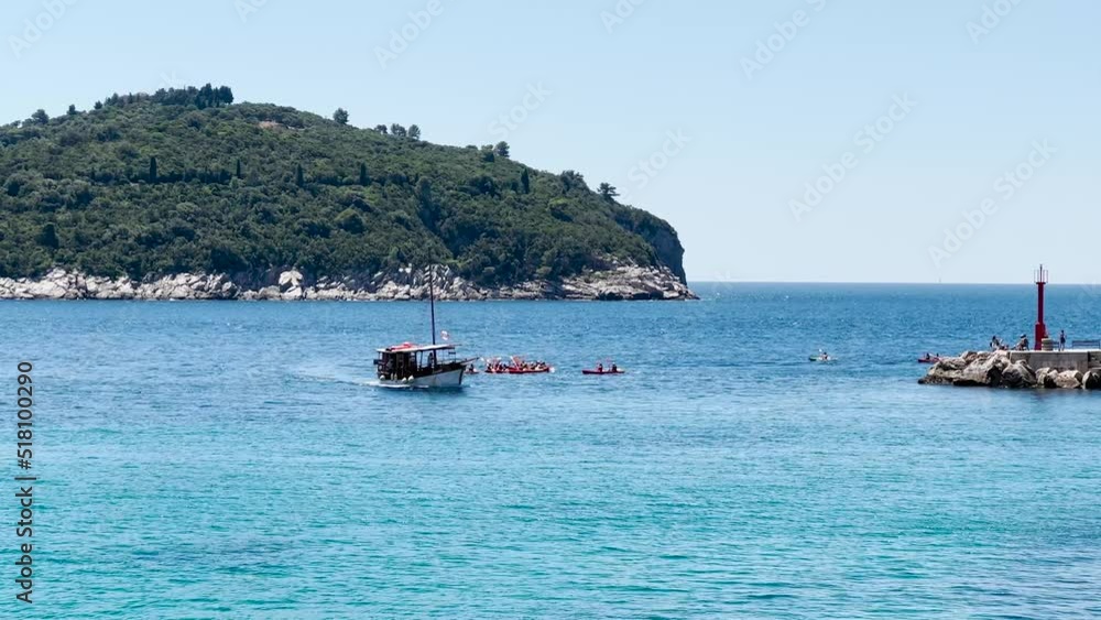 A large group of sea kayakers following their leader with a boat near them in Dubrovnik, Croatia A large group of sea kayakers following their leader with a boat near them in Dubrovnik, Croatia