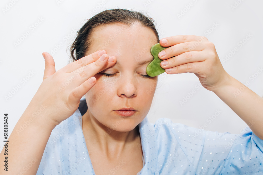 The girl makes a massage with a jade massager close-up, problem skin. The girl makes a massage with a jade massager close-up, problem skin.