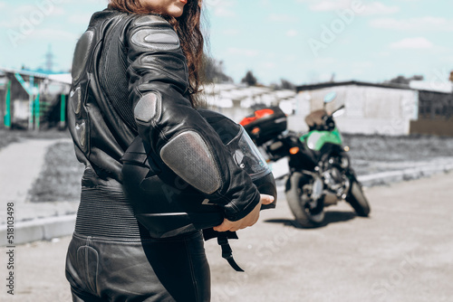 Εκτύπωση καμβά A girl in a protective motorcycle leather suit stands with her back to the background of the motorcycle