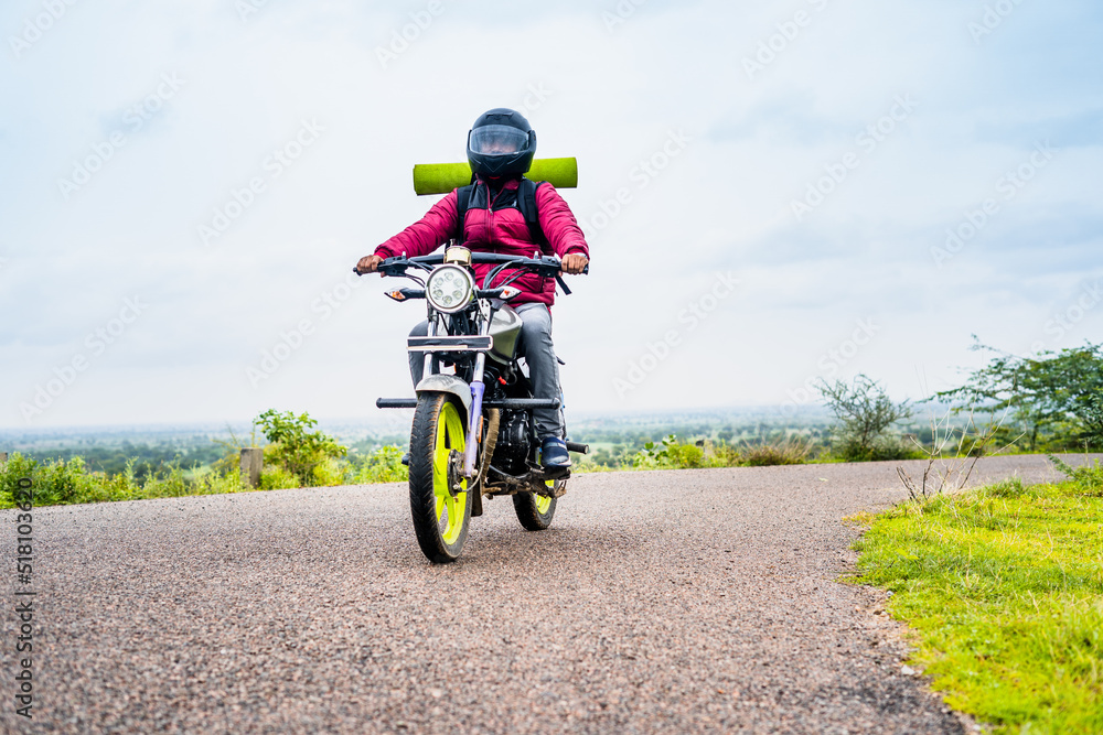 motorbke Rider with backpack traveling on motorbike near mountains on road - concept of freedom, weekend holidays and outdoor activities