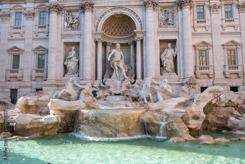 Close-up of one of the most famous landmarks in the world - Trevi Fountain in Rome in bright sunlight with water basin in the foreground. photo