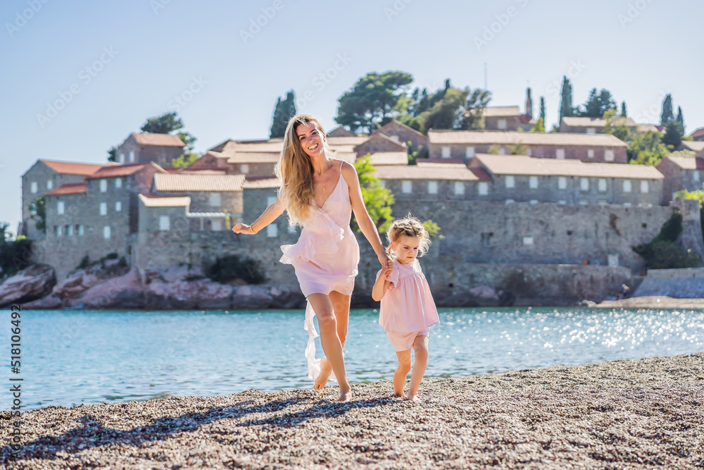 Mother and daughter tourists on background of beautiful view St. Stephen island, Sveti Stefan on the Budva Riviera, Budva, Montenegro. Travel to Montenegro concept