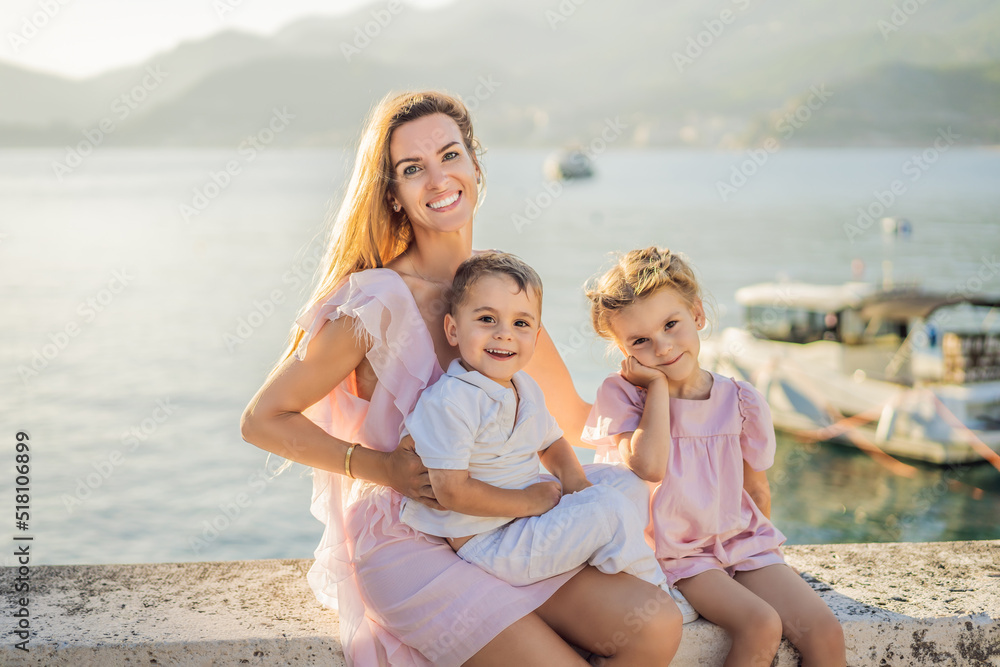 Mother and two children daughter and son tourists on background of beautiful view St. Stephen island, Sveti Stefan on the Budva Riviera, Budva, Montenegro. Travel to Montenegro concept Mother and two children daughter and son tourists on background of beautiful view St. Stephen island, Sveti Stefan on the Budva Riviera, Budva, Montenegro. Travel to Montenegro concept