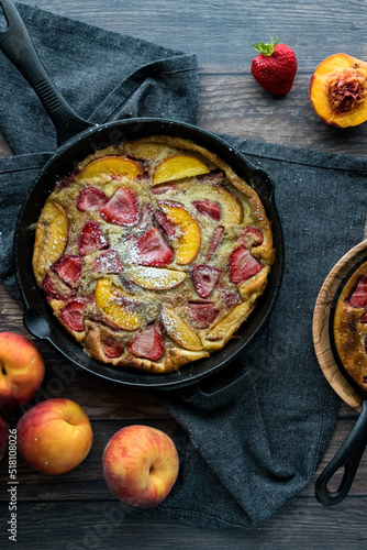 Vertical view of a strawberry peach puff pancake sprinkled with powdered sugar. photo