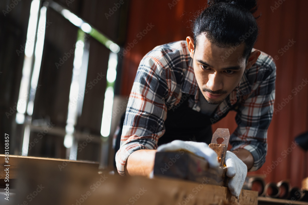 Young Asian man carpenters are using spokeshave to decorate the woodwork in woodcraft carpentry workshop. Young Asian man carpenters are using spokeshave to decorate the woodwork in woodcraft carpentry workshop.