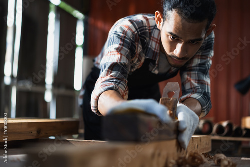 Young Asian man carpenters are using spokeshave to decorate the woodwork in woodcraft carpentry workshop.