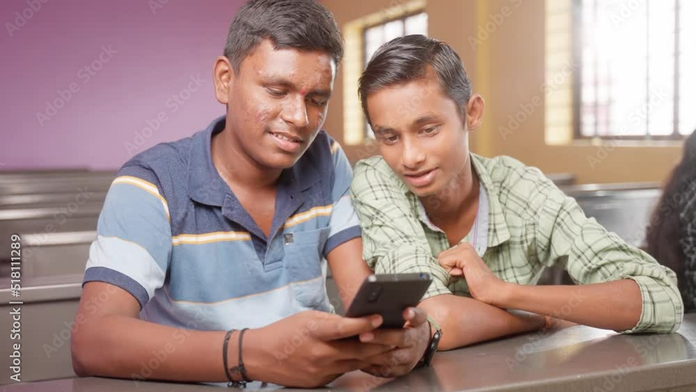 Happy smiling college students busy using mobile phone at classroom during leisure - concept of technology, friendship and social media Happy smiling college students busy using mobile phone at classroom during leisure - concept of technology, friendship and social media