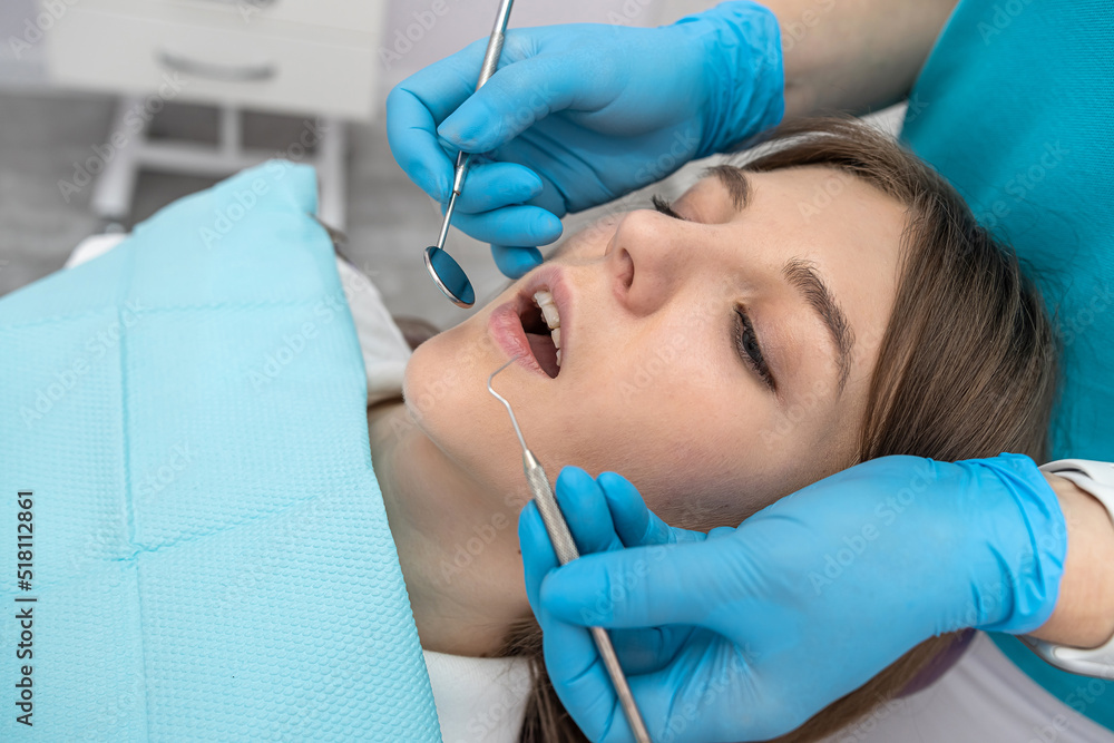 Fototapeta premium photo of a pretty woman being examined by a dentist with dental instruments in a dental chair.