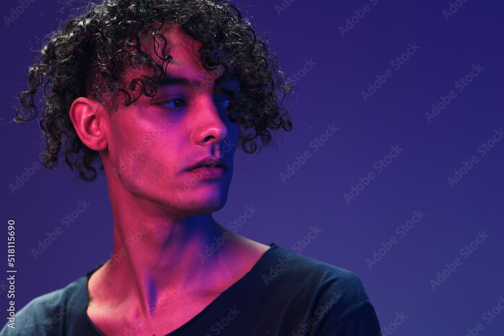Fashionable handsome curly man in black t-shirt looks aside posing isolated on color pink blue studio background. Cool fashion offer. Virtual Reality New Collection concept. Copy space for ad Fashionable handsome curly man in black t-shirt looks aside posing isolated on color pink blue studio background. Cool fashion offer. Virtual Reality New Collection concept. Copy space for ad