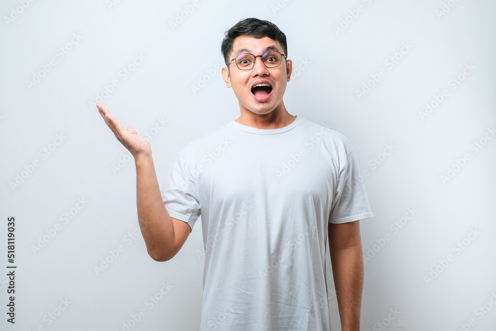 Young asian man surprised pointing with hand finger to the side, open mouth amazed expression. Young asian man surprised pointing with hand finger to the side, open mouth amazed expression.