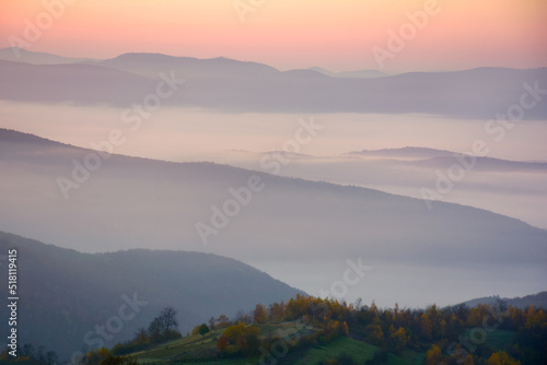 mountainous foggy landscape at sunrise. autumnal countryside misty scenery. beautiful view in to the distance valley full of morning fog