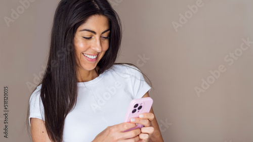 Beautiful young smiling brunette woman using mobile phone . Woman looking her phone 