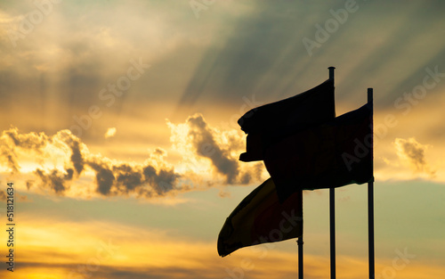 a beautiful sunset with brightly illuminated rays of the sun clouds and flying flags