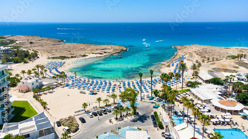 Aerial bird's eye view of Vathia Gonia beach, Ayia Napa, Famagusta, Cyprus. Landmark tourist attraction rocky bay with golden sand, sunbeds, sea restaurants in Agia Napa on summer holidays from above photo