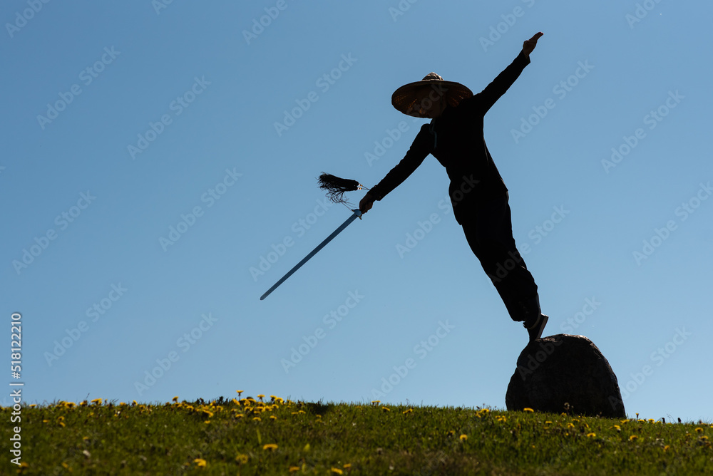 Asian woman with sword practicing taijiquan at sunset, chinese martial arts, healthy lifestyle concept. Asian woman with sword practicing taijiquan at sunset, chinese martial arts, healthy lifestyle concept.