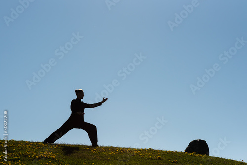 Asian woman practicing taijiquan at sunset, chinese martial arts, healthy lifestyle concept.