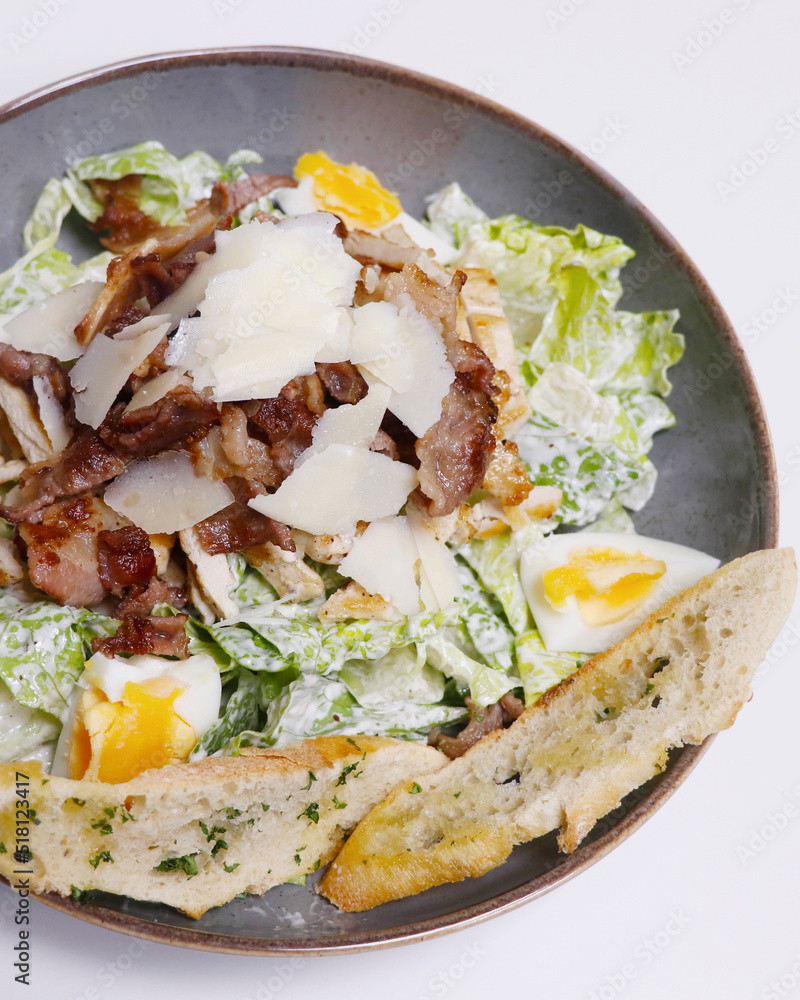 traditional caesar salad with chicken, bacon, cheese and lettuce in a serving bowl