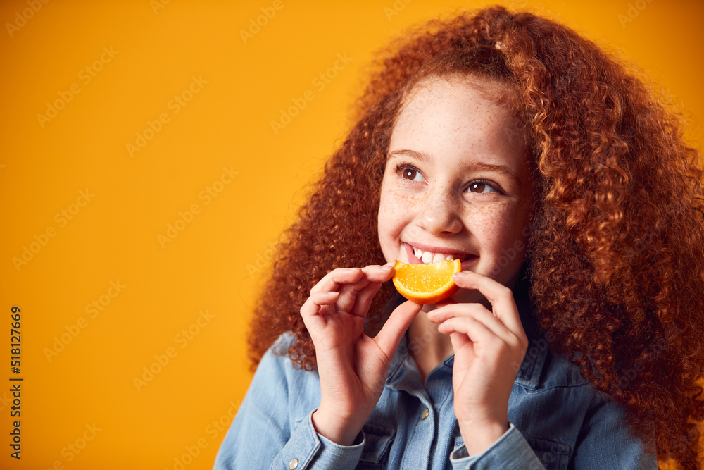 Studio Portrait Of Girl Holding Orange For Smiling Mouth Against Yellow Background Studio Portrait Of Girl Holding Orange For Smiling Mouth Against Yellow Background