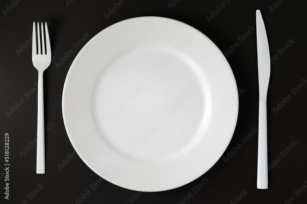 White plate and cutlery on the black background. White plate and cutlery on the black background.