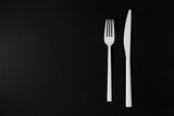 White fork and knife on the black background.