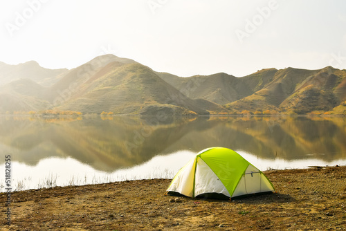 Mravaltskaro reservoir in autumn with tent and white desert canyons in background. Georgia travel destination in autumn