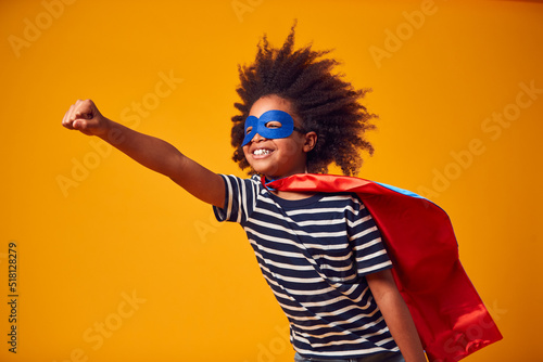 Studio Portrait Of Boy Dressed As Comic Book Superhero Against Yellow Background