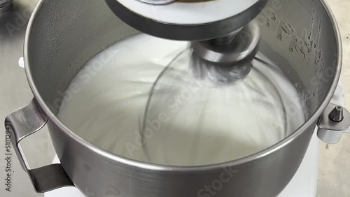 Commercial heavy duty electric mixer mixing and whipping egg white until its peak, preparation for fluffy Swiss meringue buttercream, close up shot. photo