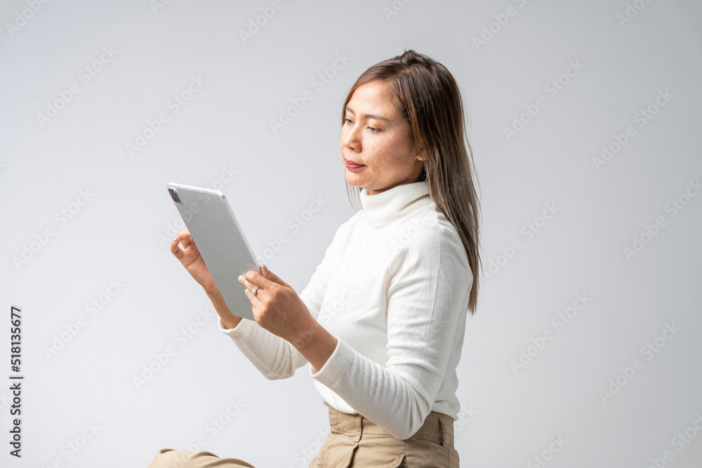 Asian woman in white shirt holding tablet in studio against white background Asian woman in white shirt holding tablet in studio against white background