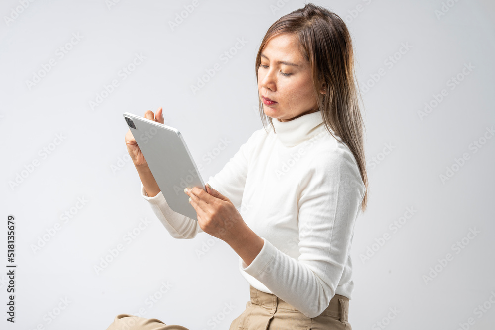 Asian woman in white shirt holding tablet in studio against white background Asian woman in white shirt holding tablet in studio against white background