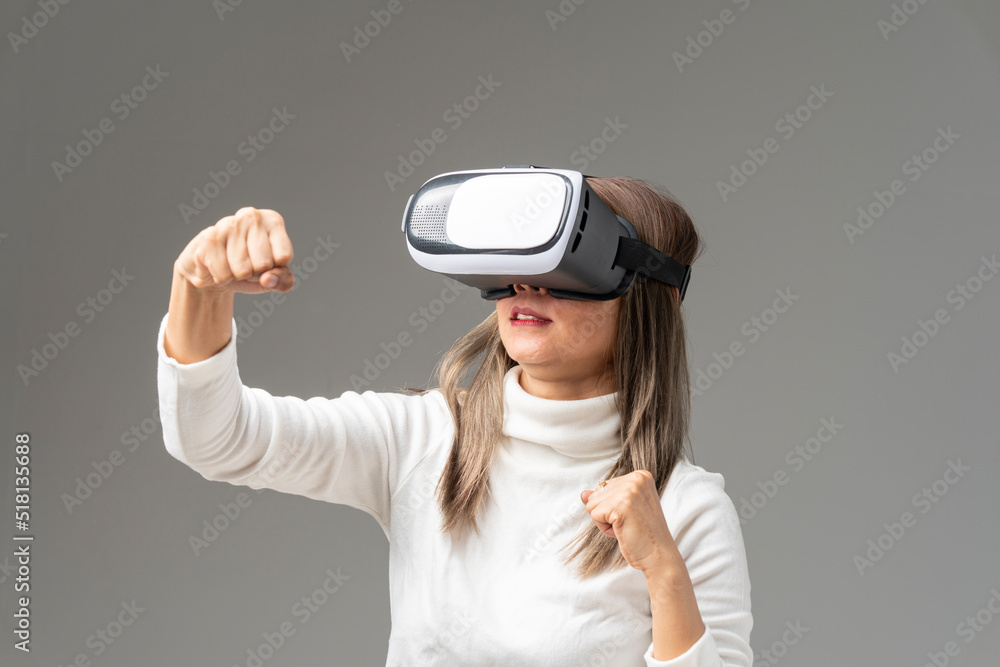 Asian woman wearing VR glasses in studio with white background with using virtual reality headset or VR glass isolate on gray background Asian woman wearing VR glasses in studio with white background with using virtual reality headset or VR glass isolate on gray background