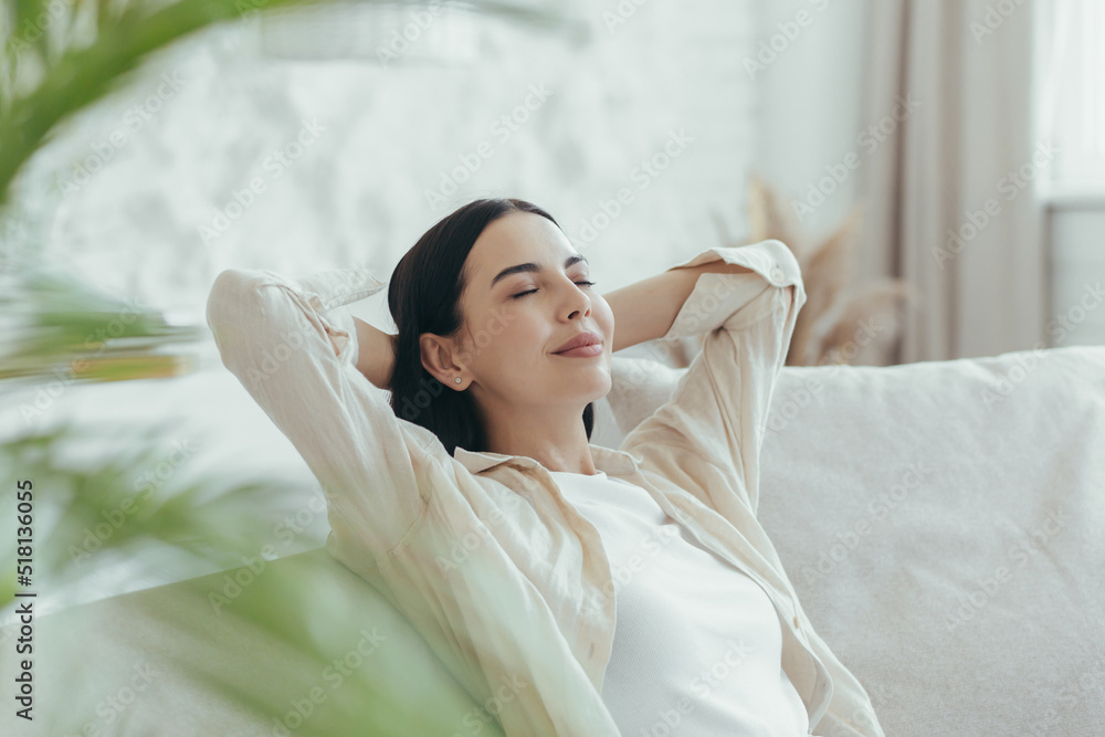 A woman is resting at home, a close-up photo, a portrait with her hands behind her head, sitting on the sofa and dozing A woman is resting at home, a close-up photo, a portrait with her hands behind her head, sitting on the sofa and dozing