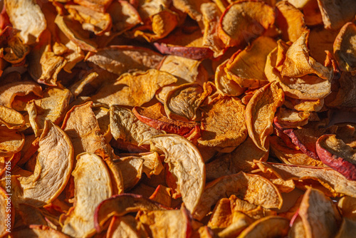 Background of dried apple slices. Dried slices of apples finely chopped for the preparation of healthy drinks, fruit drinks and compotes. Dried apple chips background selective focus top view.