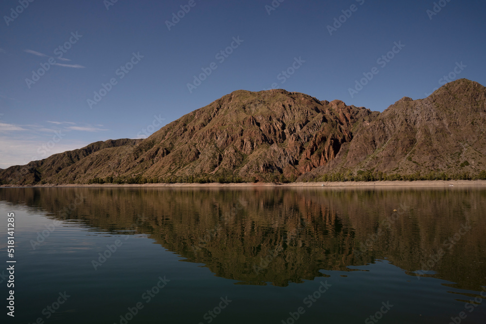 Symmetry in nature. Panorama view of the arid mountains and blue sky reflection in the lake.