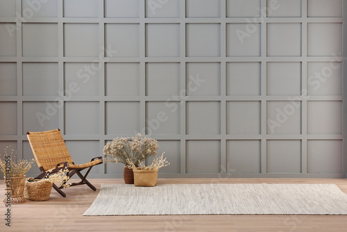 Vase of cotton flower and wicker chair decoration in front of the modern grey wall, carpet style.