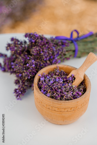 Wooden bowl with dried lavender on field background. Flower herbal tea drink. Aromatherapy  medicine ingredient. Calming beverage