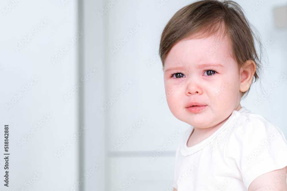 portrait unhappy crying baby child sitting on highchair on kitchen at home, baby dont want to eat food.