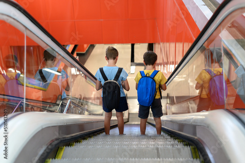 Two children with backpacks on their backs walking down a subway escalator. Concept of independents, back home alone without parents