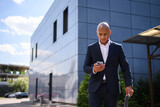 African american realtor holding paper folder and using smartphone on street 