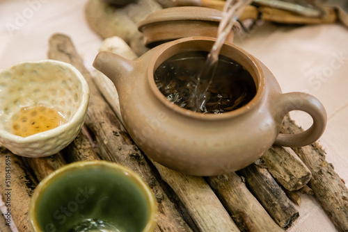 Water pouring in teapot near bowls on wooden board outdoors.