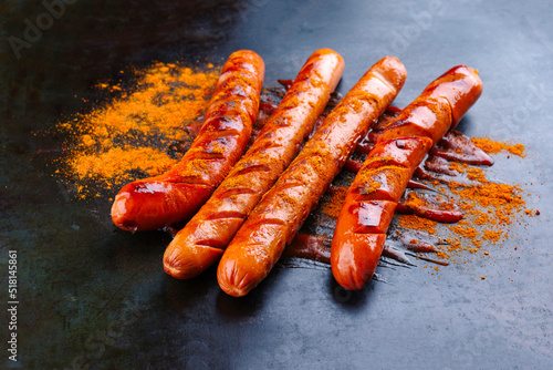 Traditionelle deutsche Barbecue Currywurst mit Ketchup und Curry Pulver serviert als close-up auf einem rustikalen schwarzen Board  photo