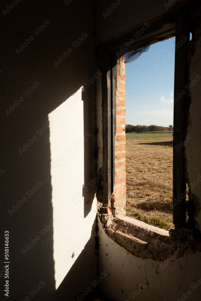 old abandoned building with a window looking to a field