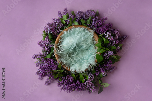 basket for a photo shoot, decorated with lilac flowers. newborn photography furniture on purple background. background decor for the photo zone. empty space for a child. photo template