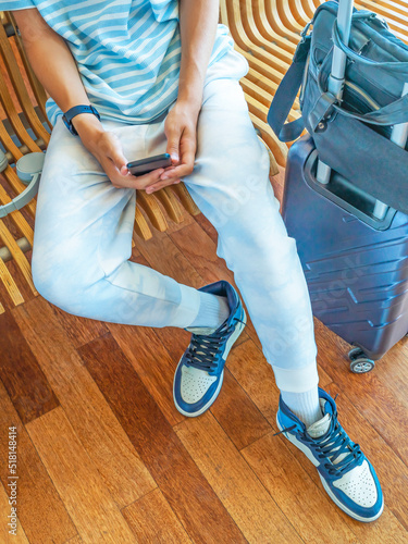 Tourist holds and uses a smartphone in his hands while waiting for a flight in the airport lounge. Vertical.