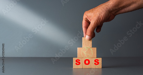 save the planet concept ,wooden blocks with green planet and SOS in red , with grey background , room for your text .